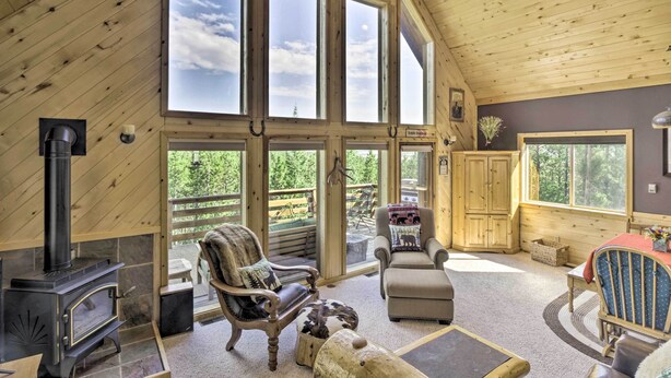 A spacious loft with large windows, a stone fireplace, and a cozy seating area. - Secluded Fairplay Home w/ Hot Tub & Mountain Views (Fairplay)