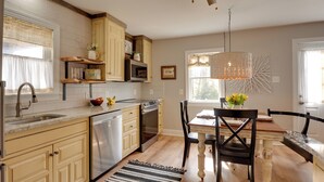 A kitchen with wooden cabinets, a dishwasher, an oven, and a dining area with a table and chairs. - Secluded Lothian Farmhouse on 45 Acres w/ Fire Pit (Lothian)