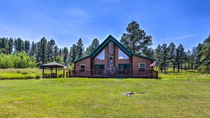 Eine Lodge mit Kamin aus Stein, großen Fenstern und einer Terrasse.