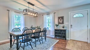 A dining room with a wooden table, black chairs, a patterned rug, and a chandelier. - Idyllic Pasadena Retreat With Garden + Hot Tub! (Pasadena)