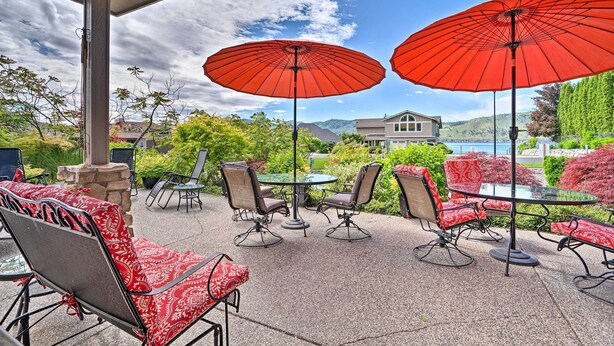 An outdoor patio with red umbrellas, a round glass table, and chairs with red and white patterned cushions. - Lake Chelan Home in Private Community w/ Lake View (Manson)