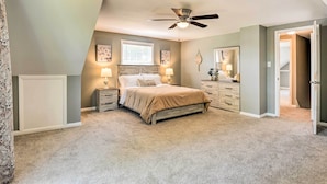 A bedroom with a bed, nightstands, a ceiling fan, a window, and a door. - Sunny Glen Burnie Home - On-site Water Access (Glen Burnie)