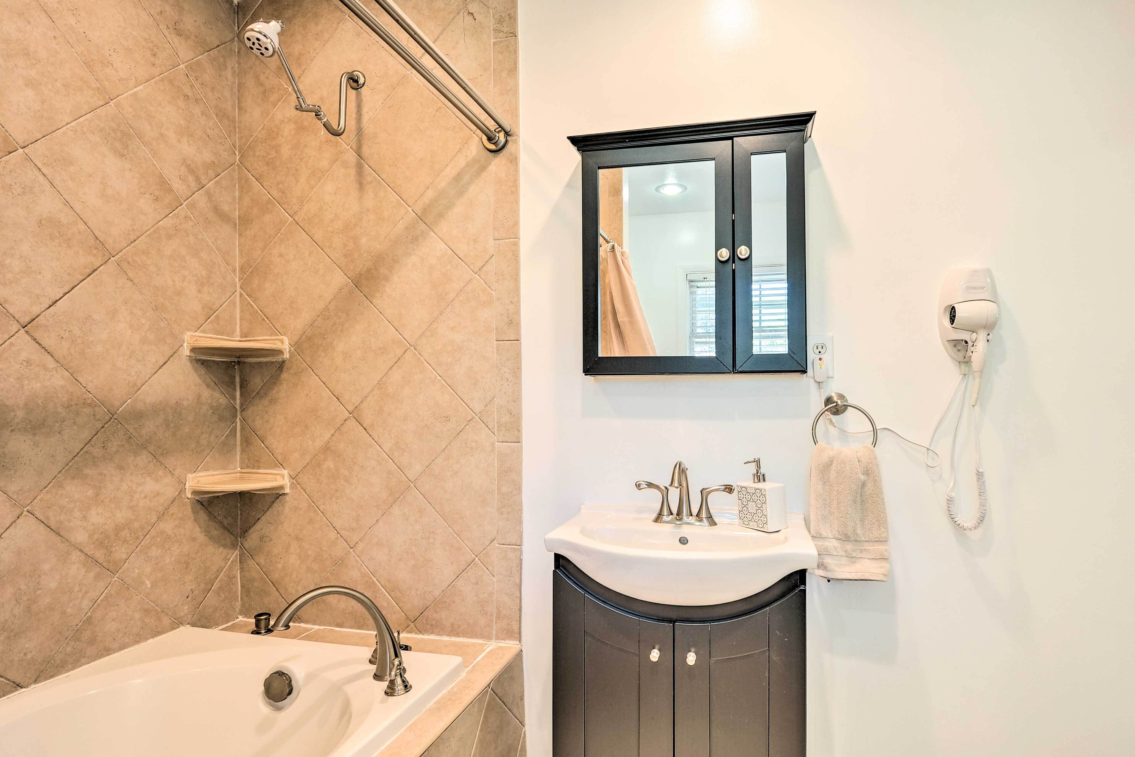 A bathroom with a bathtub, a sink, a vanity with a mirror, and a towel rack.