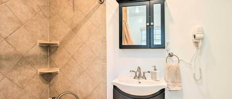 A bathroom with a bathtub, a sink, a vanity with a mirror, and a towel rack.