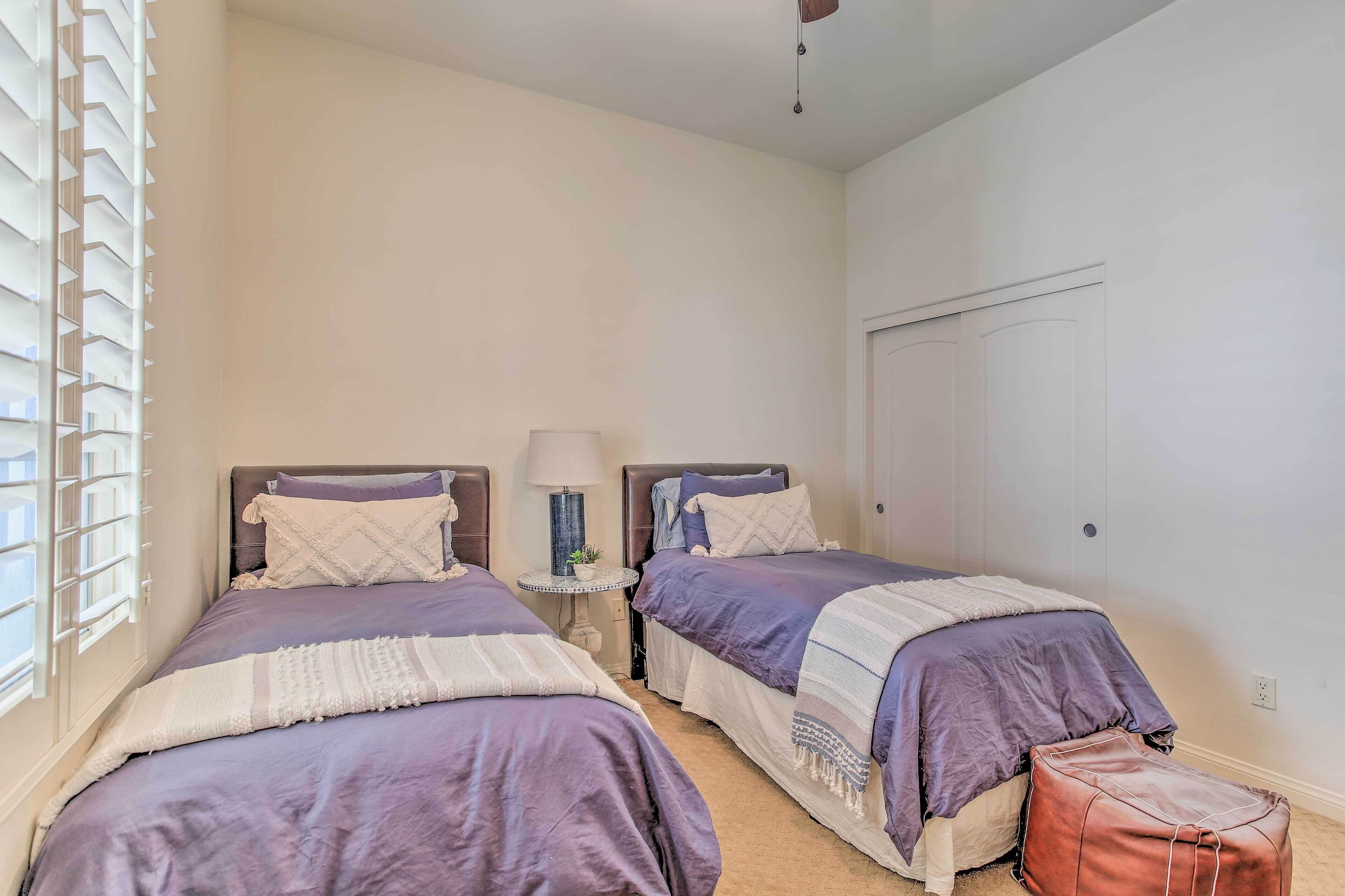 Een slaapkamer met twee bedden, een nachtkastje, een lamp en een koffer.