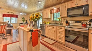 A wooden cabin interior with a kitchen featuring wooden cabinets, a microwave, an oven, and a sink. - Secluded Mountain Cabin in Wardensville! (Wardensville)