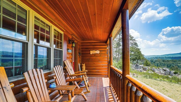 A wooden cabin with a porch featuring Adirondack chairs, a wooden railing, and a scenic view of mountains and trees. - Secluded Mountain Cabin in Wardensville! (Wardensville)
