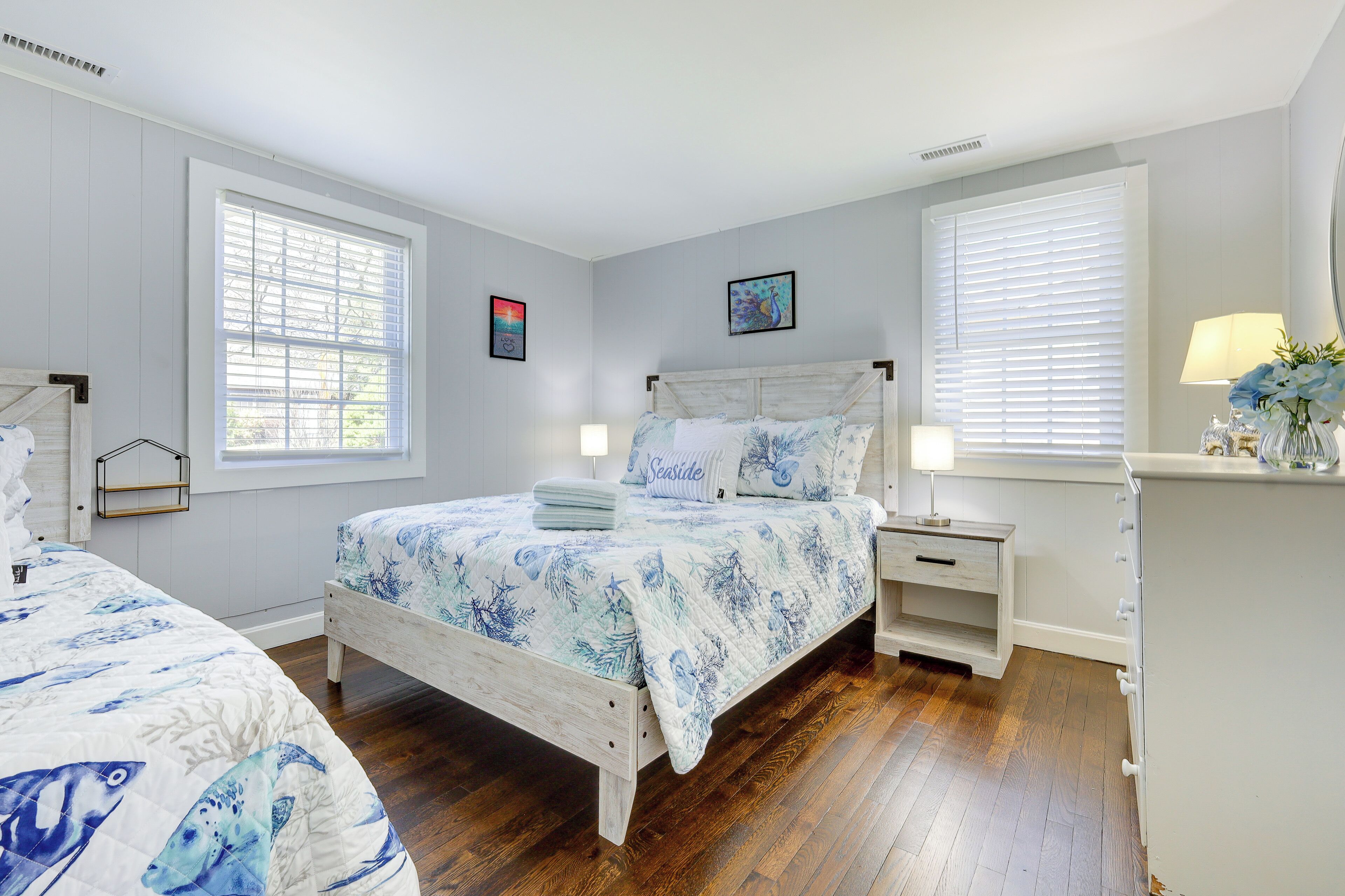 A bedroom with a bed, bedside tables, a dresser, and a window with blinds.