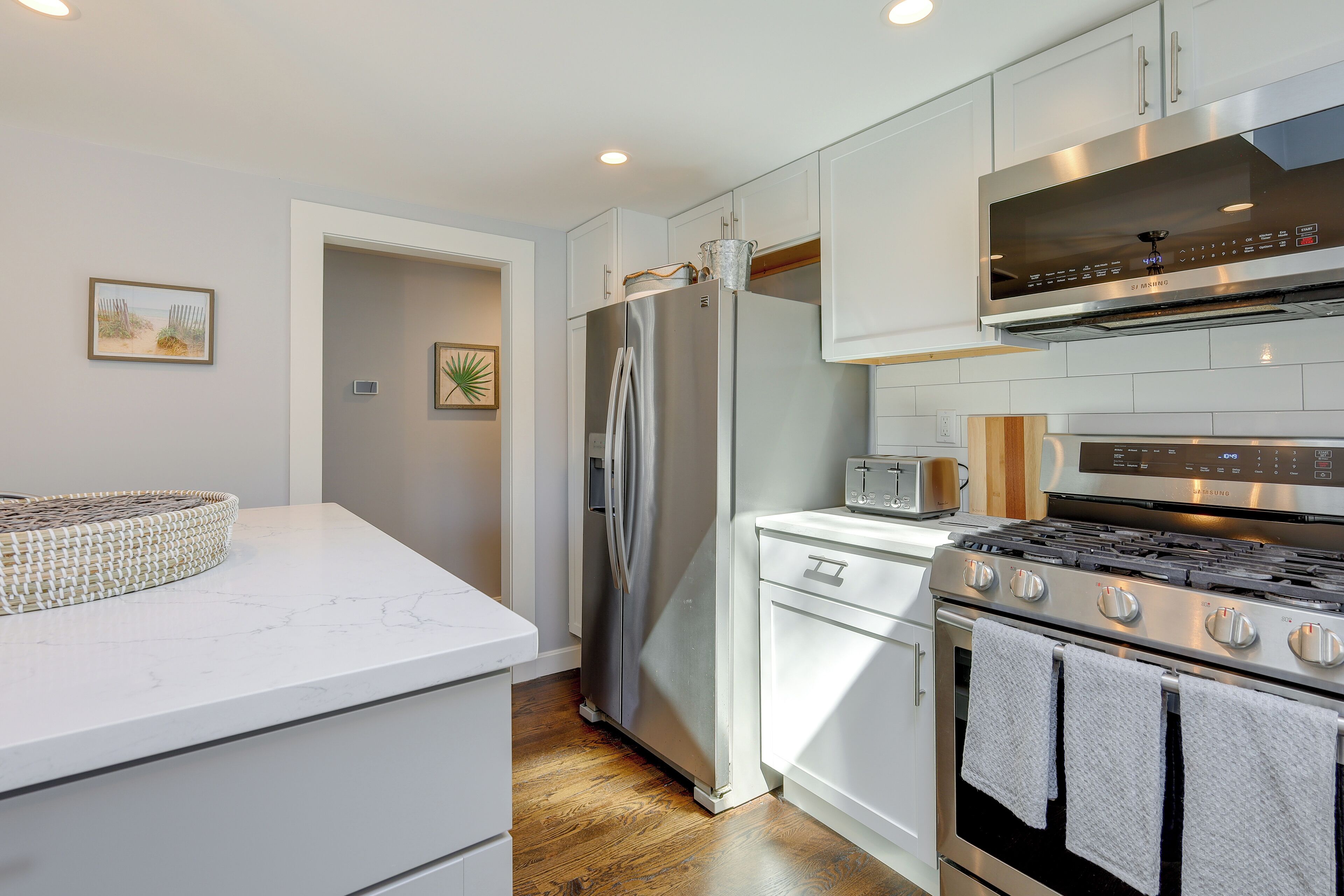 A modern kitchen with white cabinetry, a stainless steel refrigerator, a built-in oven, and a microwave.