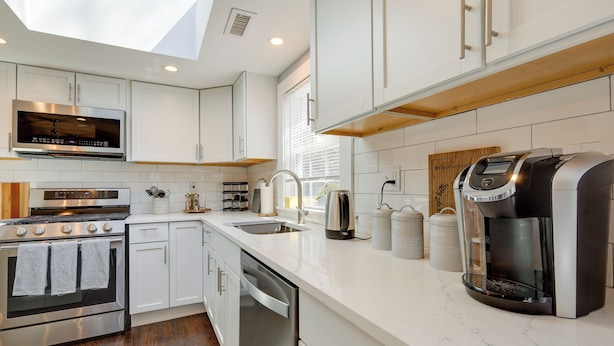 A modern kitchen with white cabinetry, stainless steel appliances, a coffee maker, and a skylight. - Families Welcome! Home 2 Mi to Craigville Beach (Hyannis)