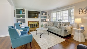 A living room with a fireplace, a sofa, a coffee table, and a side table. - Families Welcome! Home 2 Mi to Craigville Beach (Hyannis)