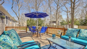 An outdoor patio with blue furniture, a table, and an umbrella. - Families Welcome! Home 2 Mi to Craigville Beach (Hyannis)