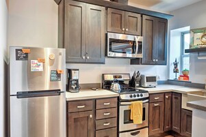 A modern kitchen with stainless steel appliances, dark wooden cabinets, and a built-in microwave.