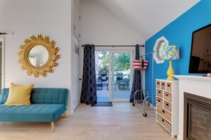 A living room with a teal sofa, a golden mirror, a white fireplace, and a blue accent wall. - 3 Mi to Beach: Couple's Escape in Marston Mills (Marstons Mills)