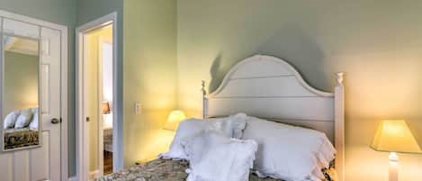 Een netjes opgemaakt bed met bloemenbedrukking, een wit hoofdeinde en twee bedlampjes.