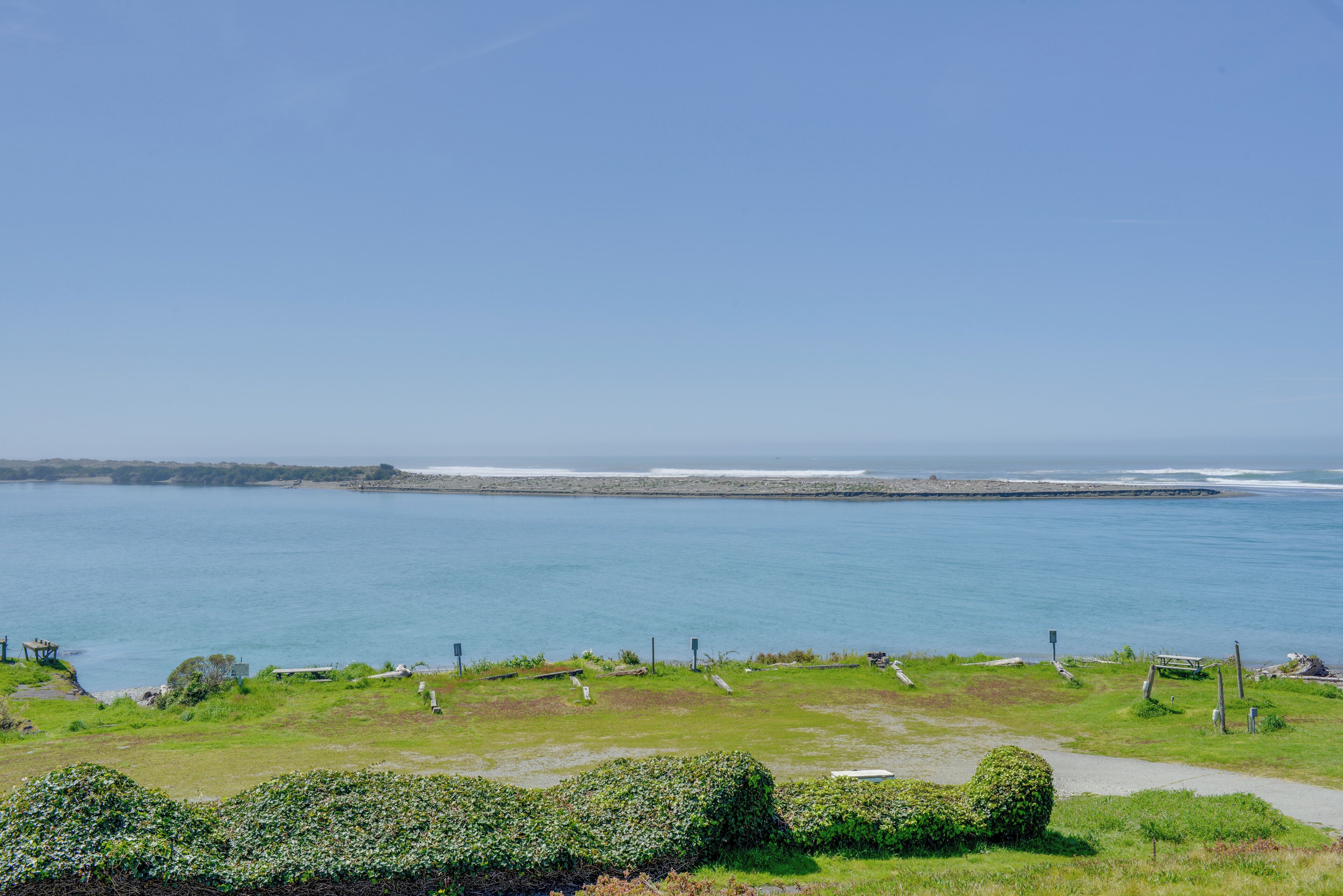 A coastal landscape with a grassy area, a pathway, and a view of the sea.