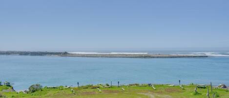 A coastal landscape with a grassy area, a pathway, and a view of the sea.