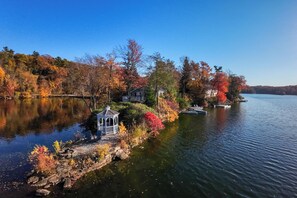 Un chalet au bord du lac, doté d’un belvédère, entouré d’un feuillage automnal et offrant une vue dégagée sur le lac.