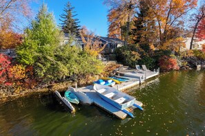 Un quai avec des bateaux, un sentier pavé de pierres et des arbres aux couleurs automnales.