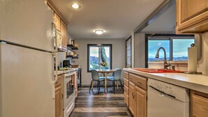 A modern kitchen with wooden cabinets, a dishwasher, and a dining area with a table and chairs.