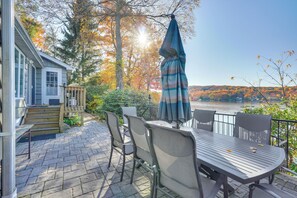 Une terrasse avec une table et des chaises, donnant sur un lac aux couleurs automnales.
