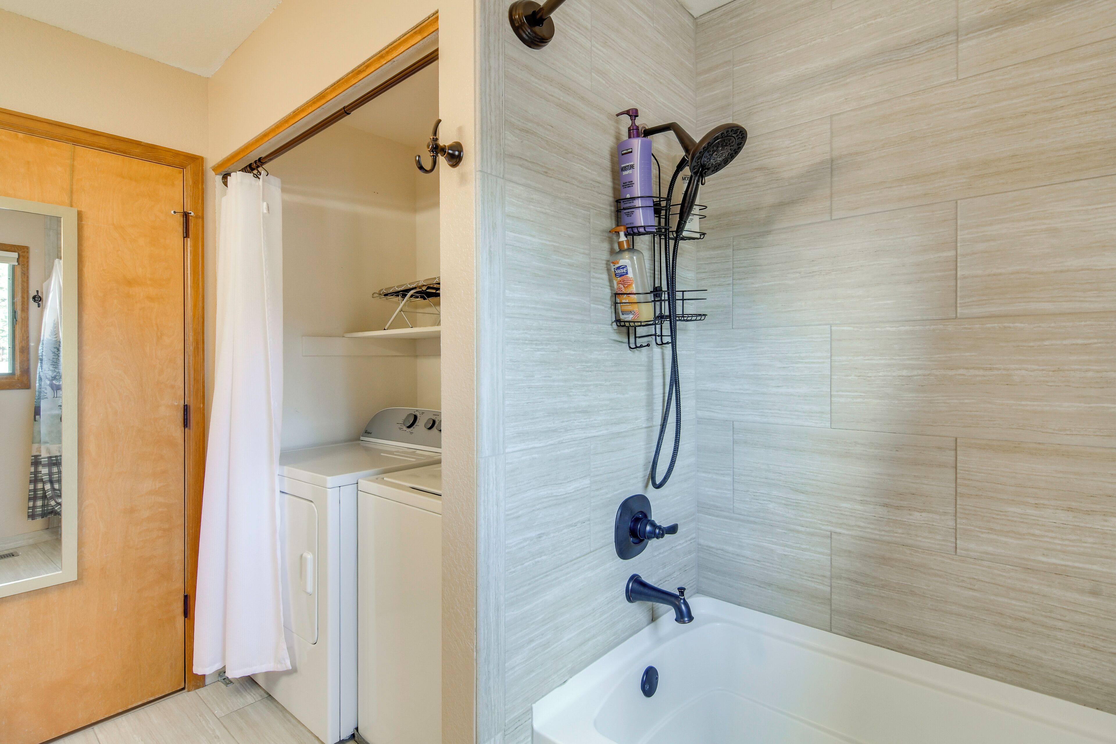 A bathroom with a shower, a sink, and a washing machine.