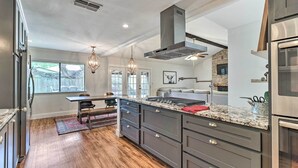 A modern kitchen with dark gray cabinets, stainless steel appliances, and a marble countertop. - Pet-friendly Austin Ranch Home w/ Fire Pit! (Austin)