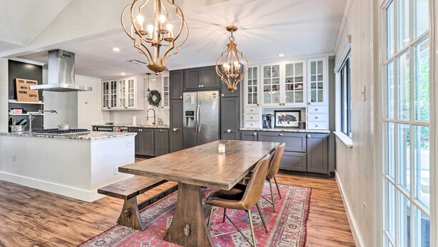 A spacious kitchen with a central island, dark cabinets, and a large window. - Pet-friendly Austin Ranch Home w/ Fire Pit! (Austin)