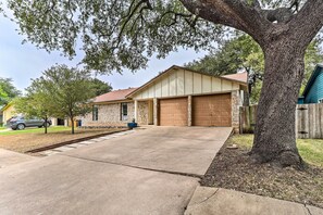 A residential house with a garage, driveway, and a large tree. - Pet-friendly Austin Ranch Home w/ Fire Pit! (Austin)