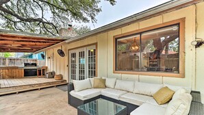 A covered outdoor seating area with a sectional sofa, a glass-top coffee table, and a wooden deck. - Pet-friendly Austin Ranch Home w/ Fire Pit! (Austin)