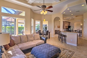 A spacious living room with a large sofa, ottoman, and a ceiling fan. - Lavish Naples Resort Villa: Private Pool & Hot Tub (Naples)