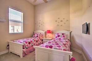A bedroom with two beds, a window, a wall-mounted TV, and a ceiling fan. - Lavish Naples Resort Villa: Private Pool & Hot Tub (Naples)