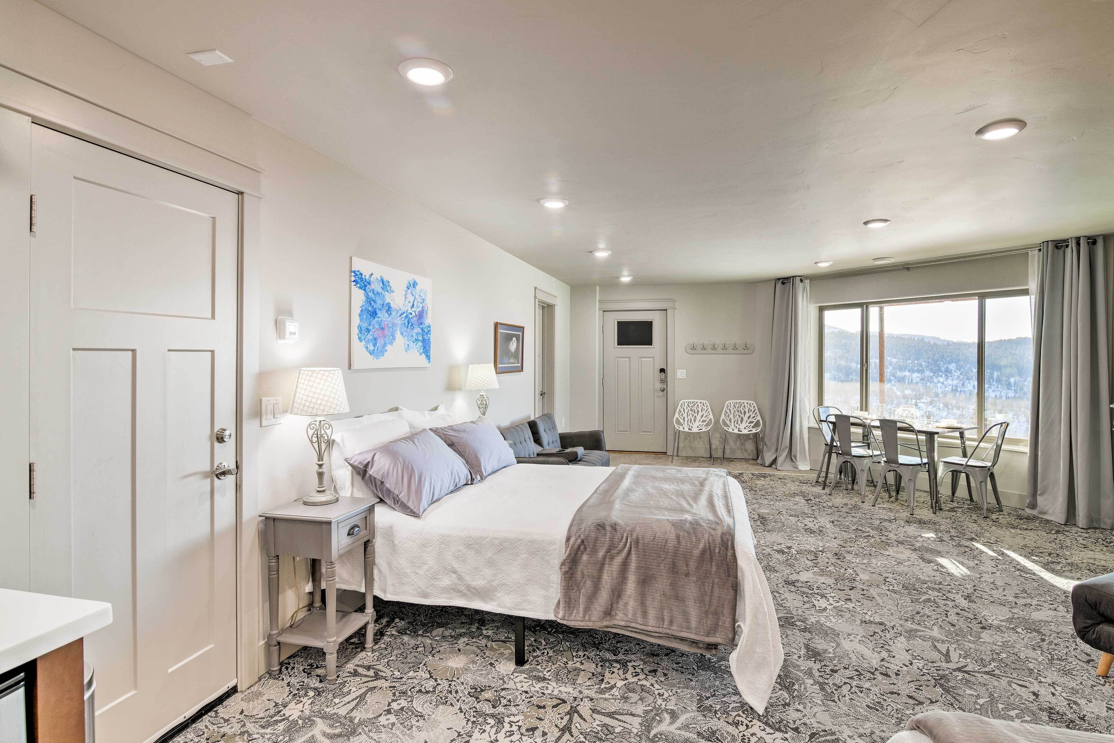 Une chambre d’hôtel équipée d’un lit, de tables de chevet, d’un bureau, d’une chaise et offrant une vue sur l’extérieur.