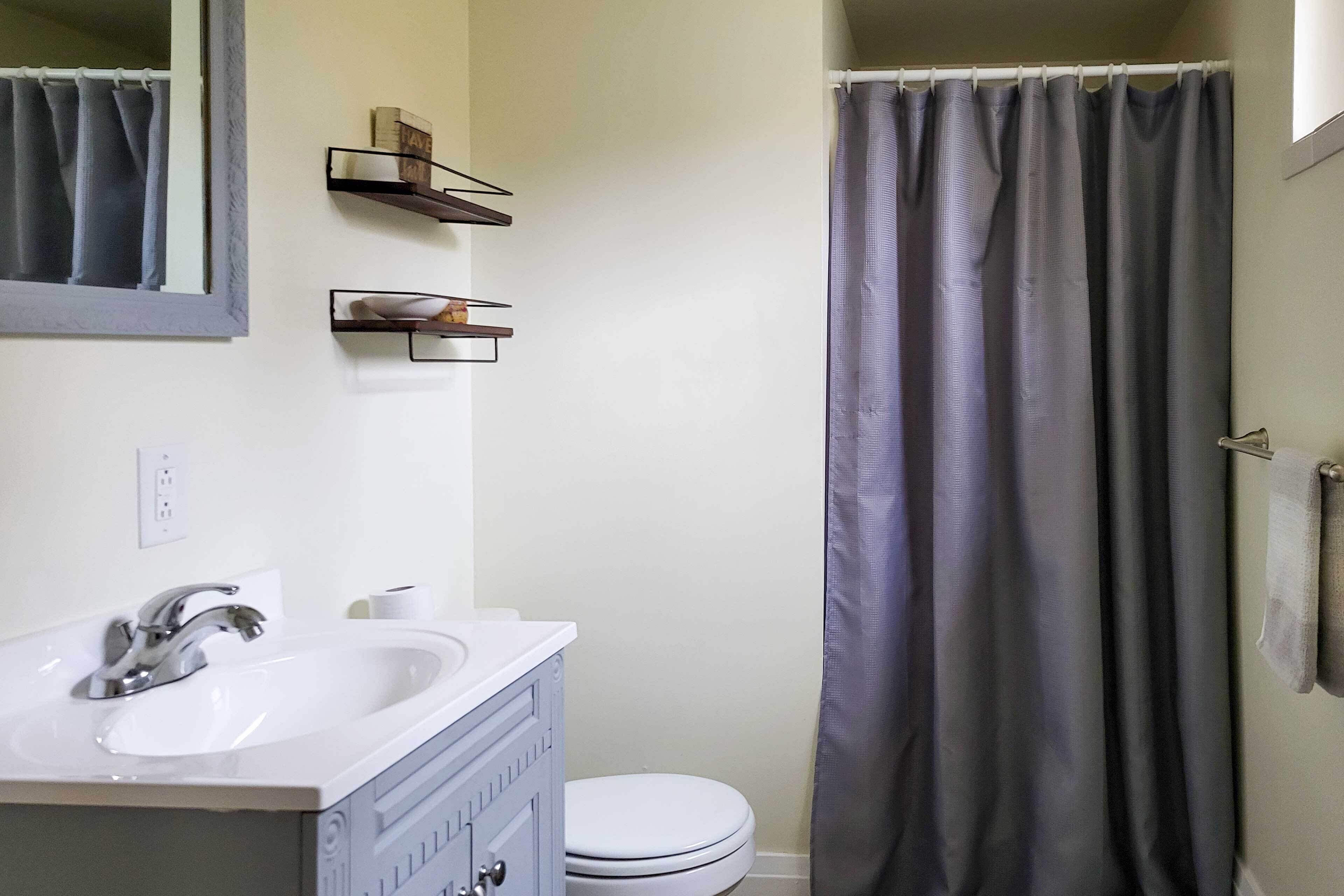 A bathroom with a white sink, a mirror, a toilet, and a shower curtain.