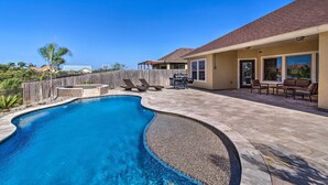 A backyard with a swimming pool, patio furniture, and a wooden fence. - South Padre Paradise w/ Saltwater Pool Near Golf! (Port Isabel)