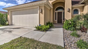 A single-story house with a beige facade, a garage, and a well-maintained front yard with various plants. - South Padre Paradise w/ Saltwater Pool Near Golf! (Port Isabel)