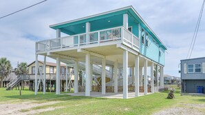 A two-story house with a balcony, a covered porch, and a staircase leading to the upper level. - Furnished Deck + Ocean Views: Surfside Beach Home (Freeport)