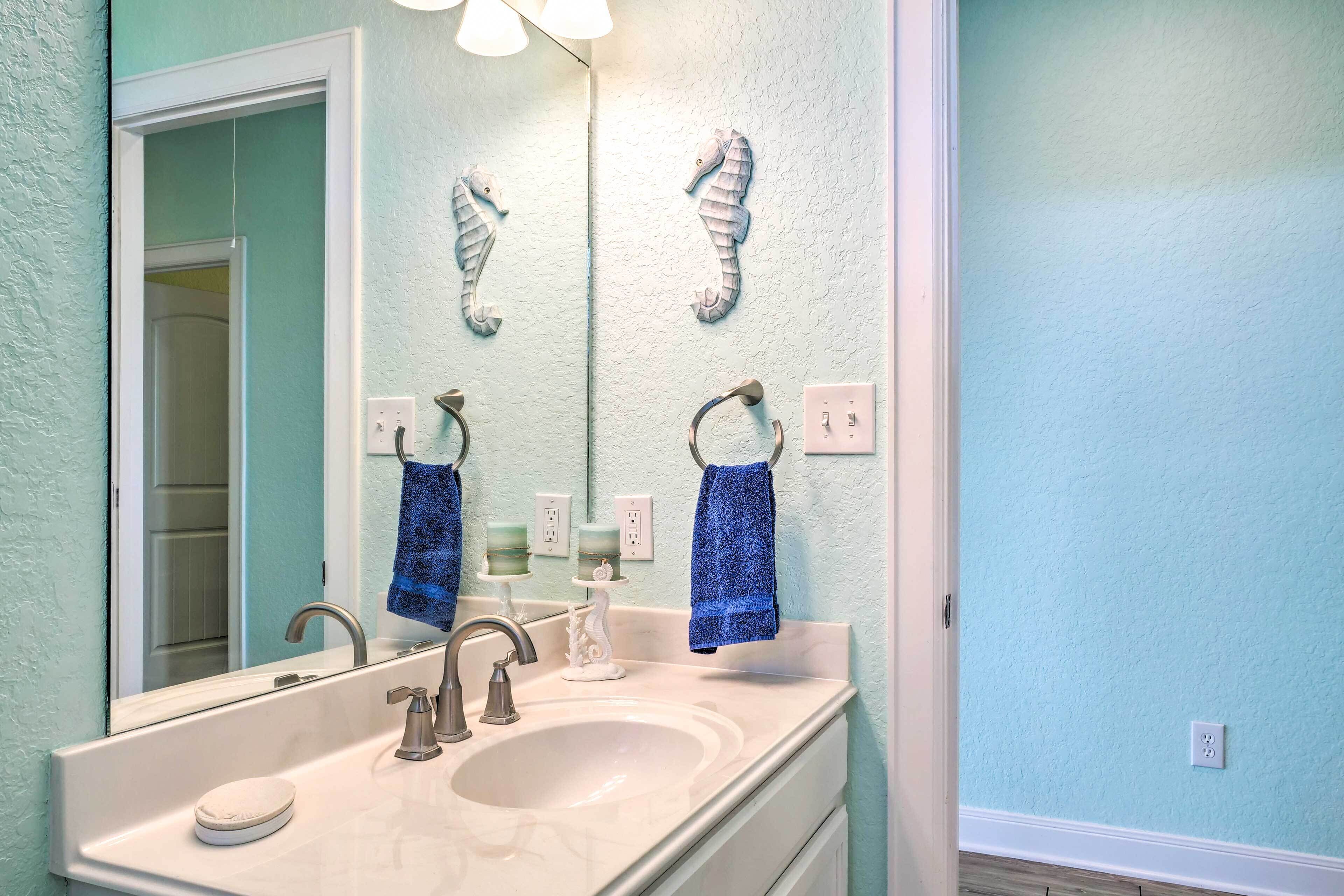Une salle de bain avec un grand miroir, deux radiateurs fixés au mur, un lavabo avec un robinet et deux serviettes suspendues à des crochets.