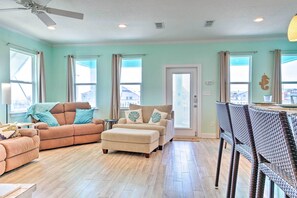 A living room with a sofa, ottoman, and wicker chairs. - Furnished Deck + Ocean Views: Surfside Beach Home (Freeport)