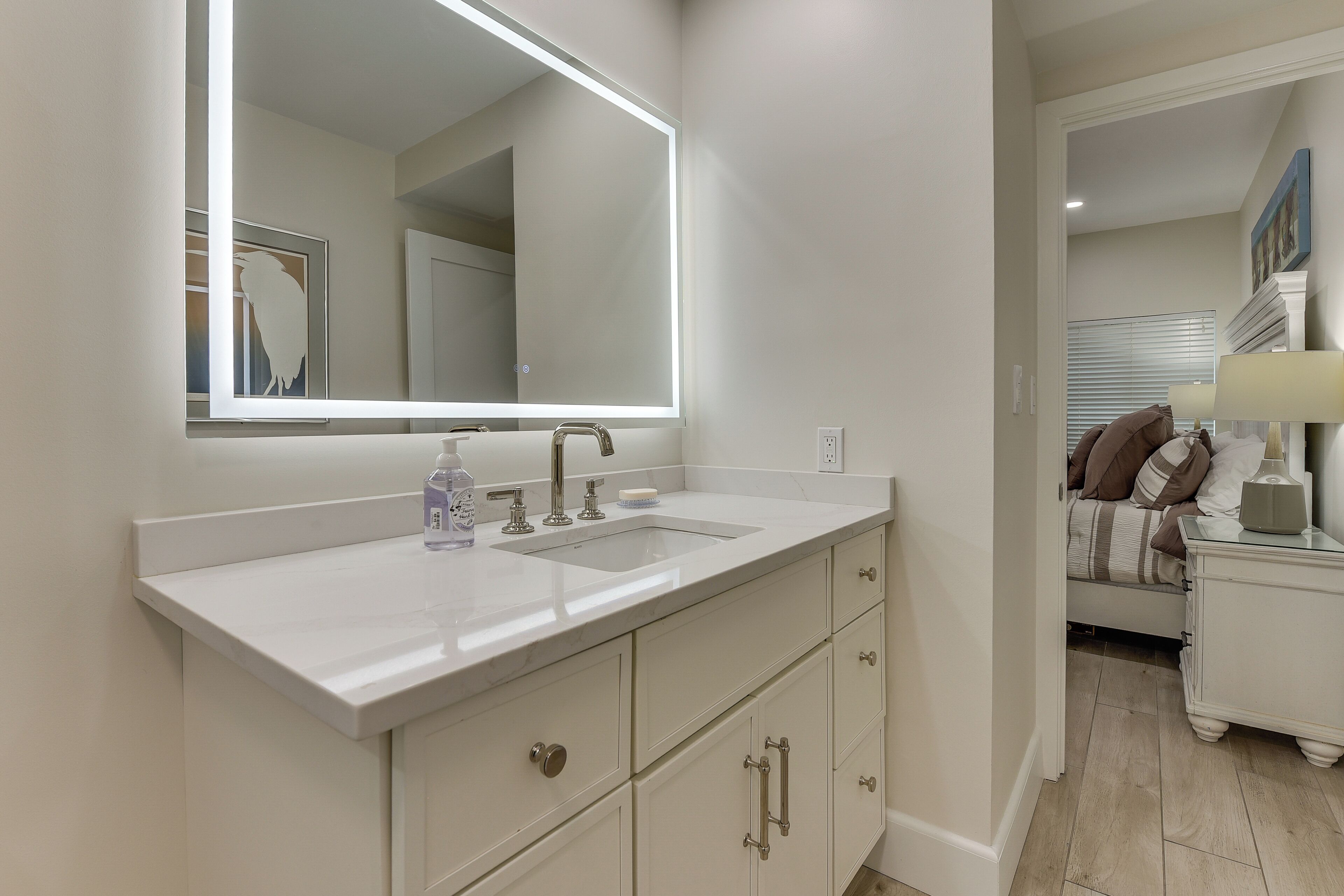 A bathroom with a large mirror, two sinks, and a cabinet.