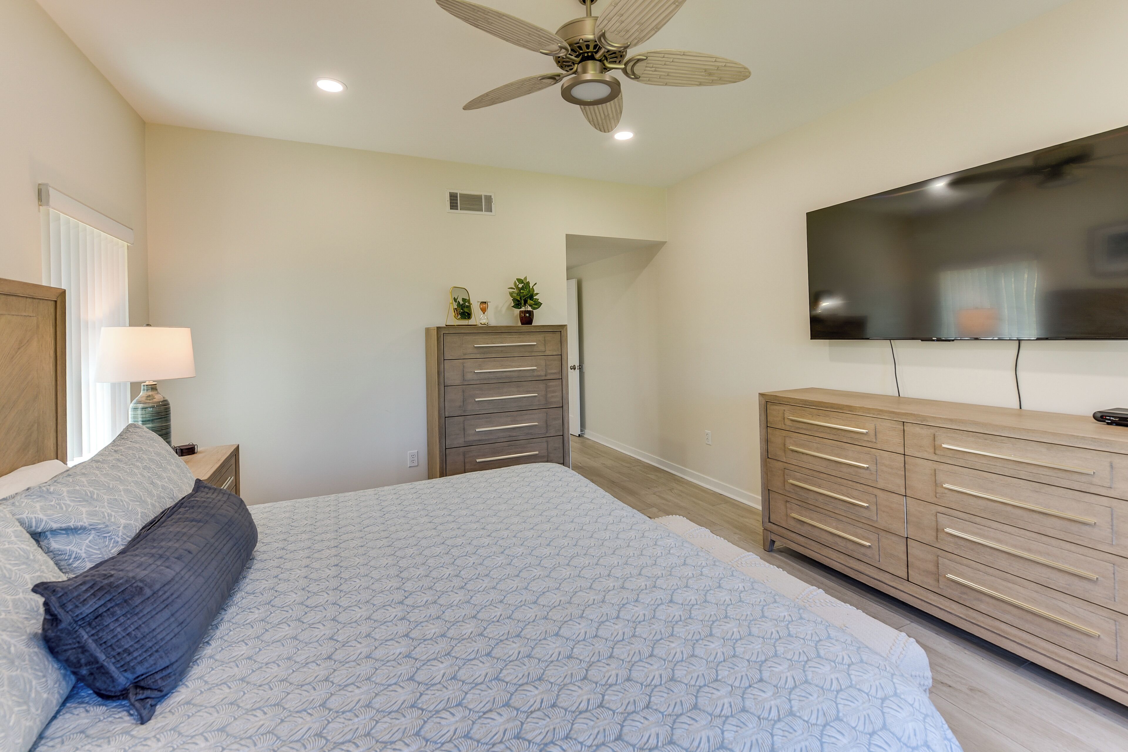 Un dormitorio con cama, cómoda, televisor, ventilador de techo y mesita de noche.