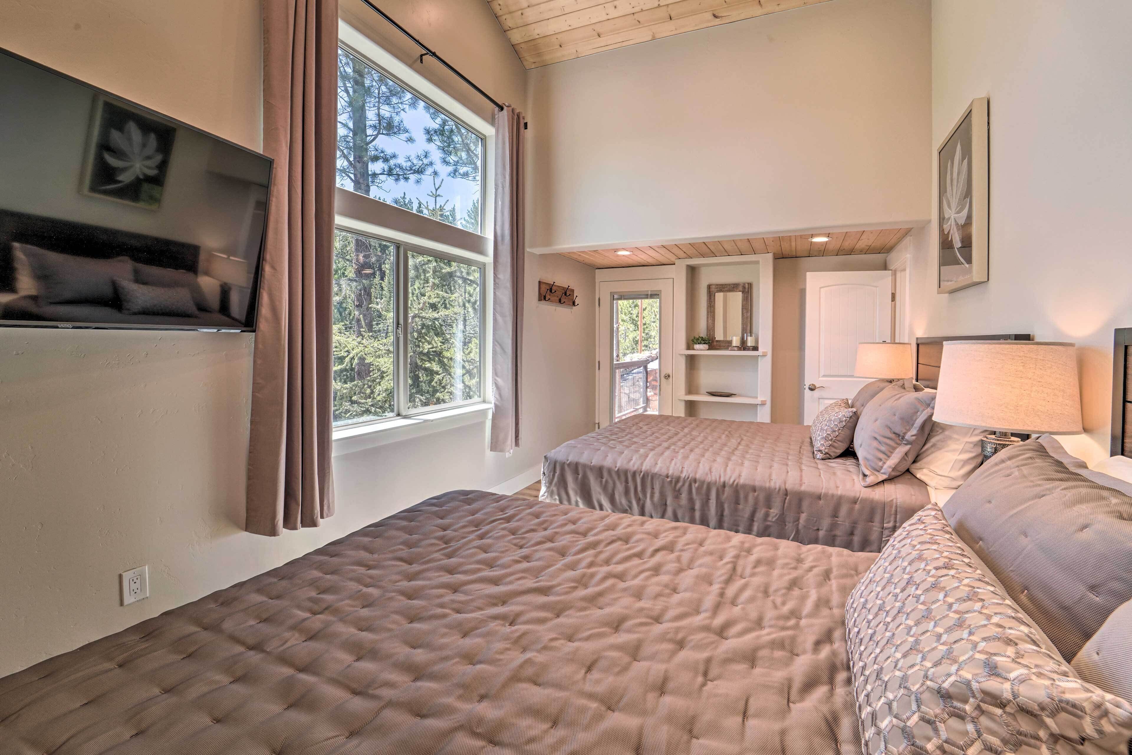 Ein Schlafzimmer mit zwei Betten, einem fensterbepflanzten Fenster, einer Kommode mit Dekoration und einer Tür zu einem anderen Raum.