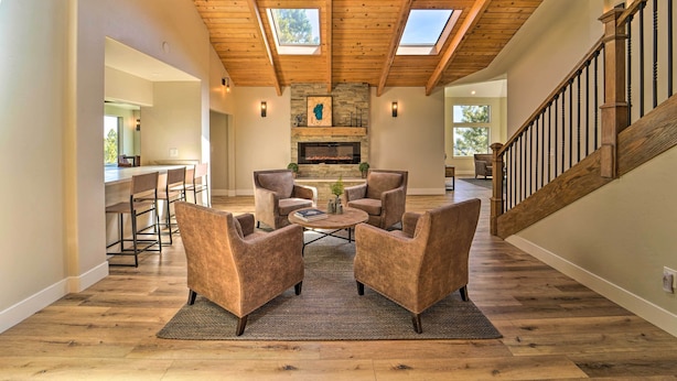A spacious living room with a high ceiling, wooden beams, a fireplace, and a staircase. - Hot Tub, Pool Table: Luxe Reno Chalet w/ Mtn View! (Reno)