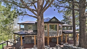 A multi-level wooden cabin with stone accents, surrounded by trees and featuring a deck with stone railings. - Hot Tub, Pool Table: Luxe Reno Chalet w/ Mtn View! (Reno)