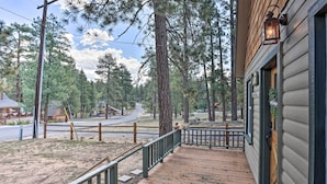 A wooden deck with a railing, a porch, and a view of a road and trees. - Walk to Big Bear Lake: Cozy Cabin w/ Deck (Big Bear Lake)