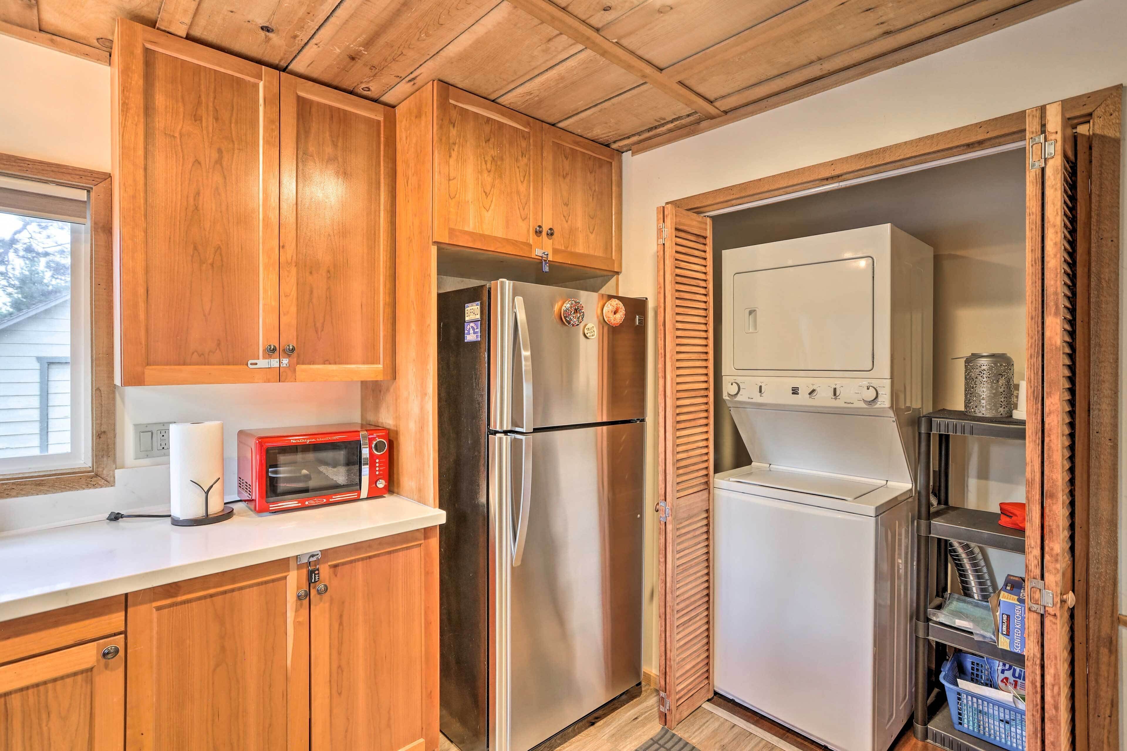 A compact kitchen with wooden cabinets, a stainless steel refrigerator, a microwave, and a built-in oven.