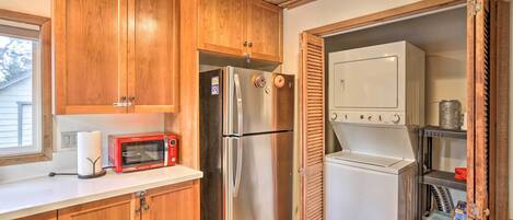 A compact kitchen with wooden cabinets, a stainless steel refrigerator, a microwave, and a built-in oven.