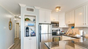 Une cuisine moderne avec des meubles blancs, des appareils en acier inoxydable et un plan de travail en granit.