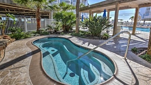 Une piscine au design incurvé, entourée de carreaux de pierre et de palmiers.