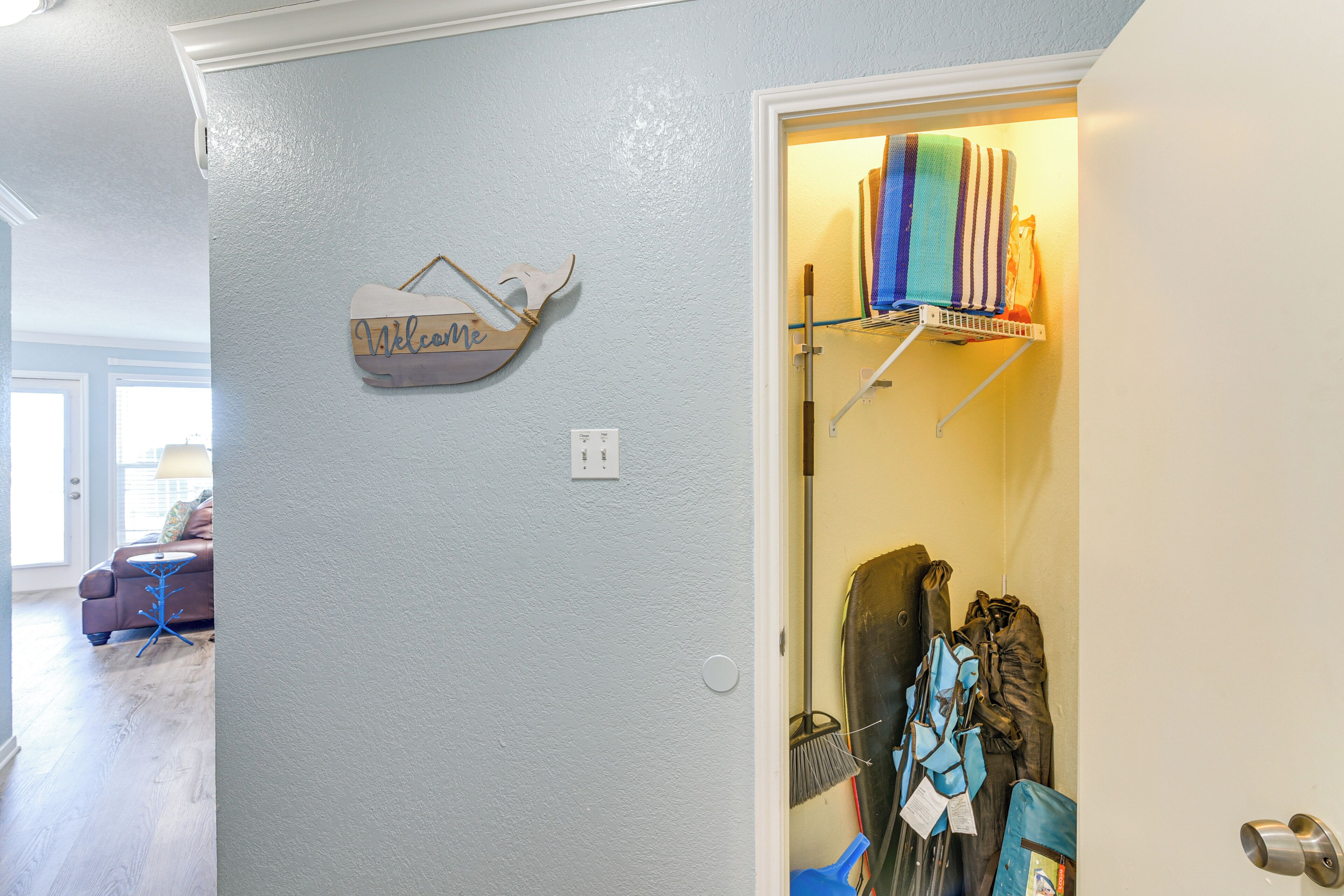 A hallway with a blue wall, a welcome sign, and a coat rack with hanging items.
